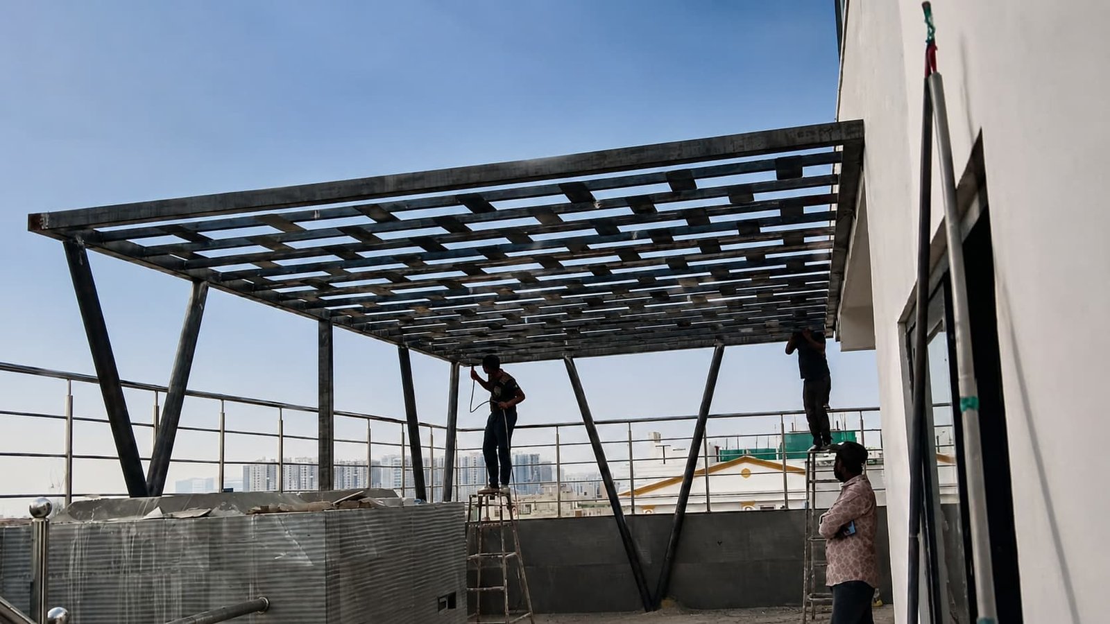 Workers fabricating a custom rooftop iron pergola frame in Kokapet Hyderabad