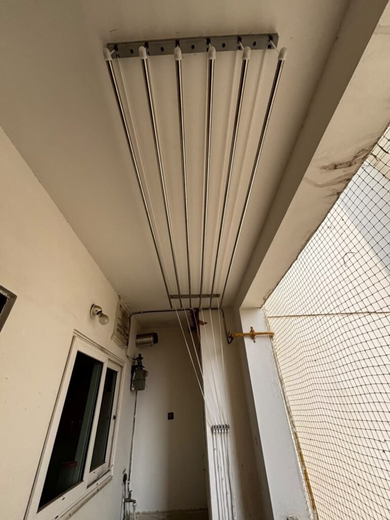 Existing ceiling-mounted cloth drying hanger with metal rods and pulley ropes in a residential balcony at Lanco Hills, Manikonda, Hyderabad.