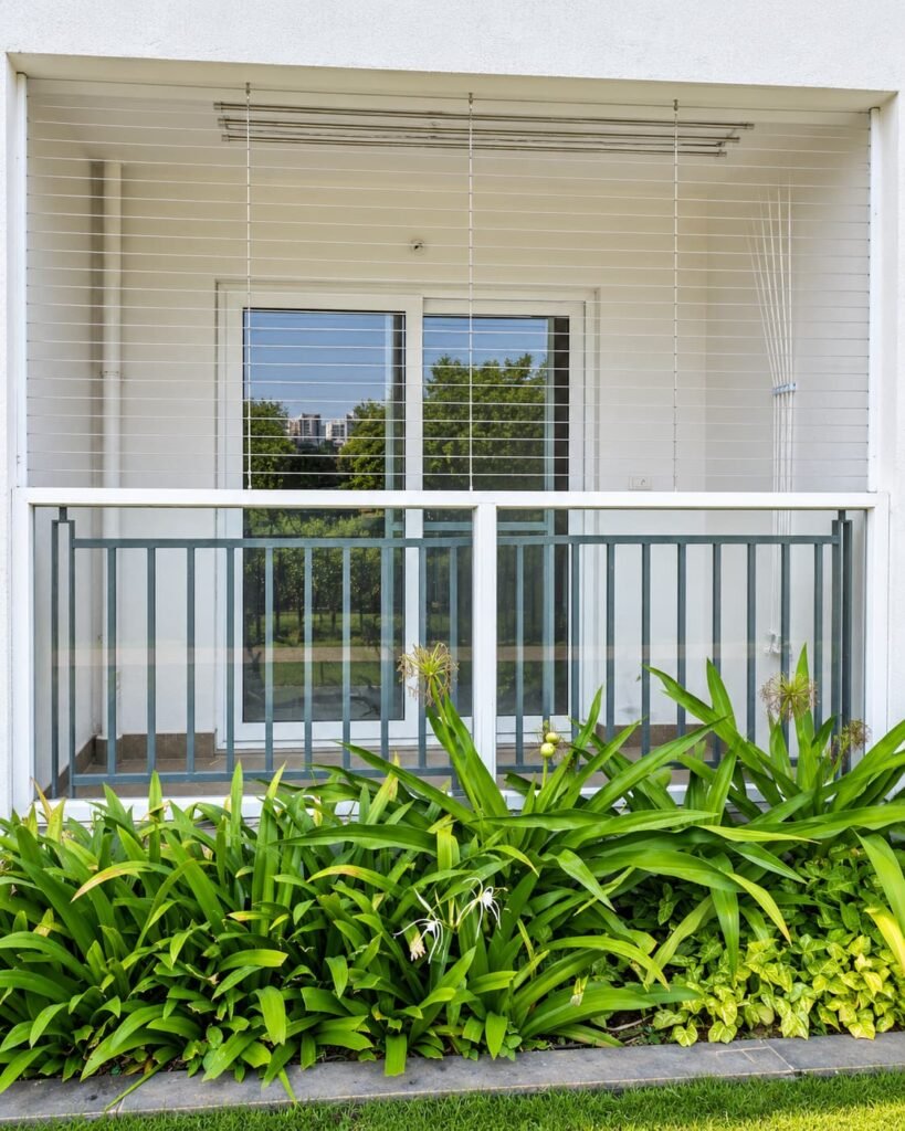 Hallmark Sunnyside invisible grill with ceiling-mounted cloth hanger in an apartment balcony, installed by Perfect Screens in Hyderabad